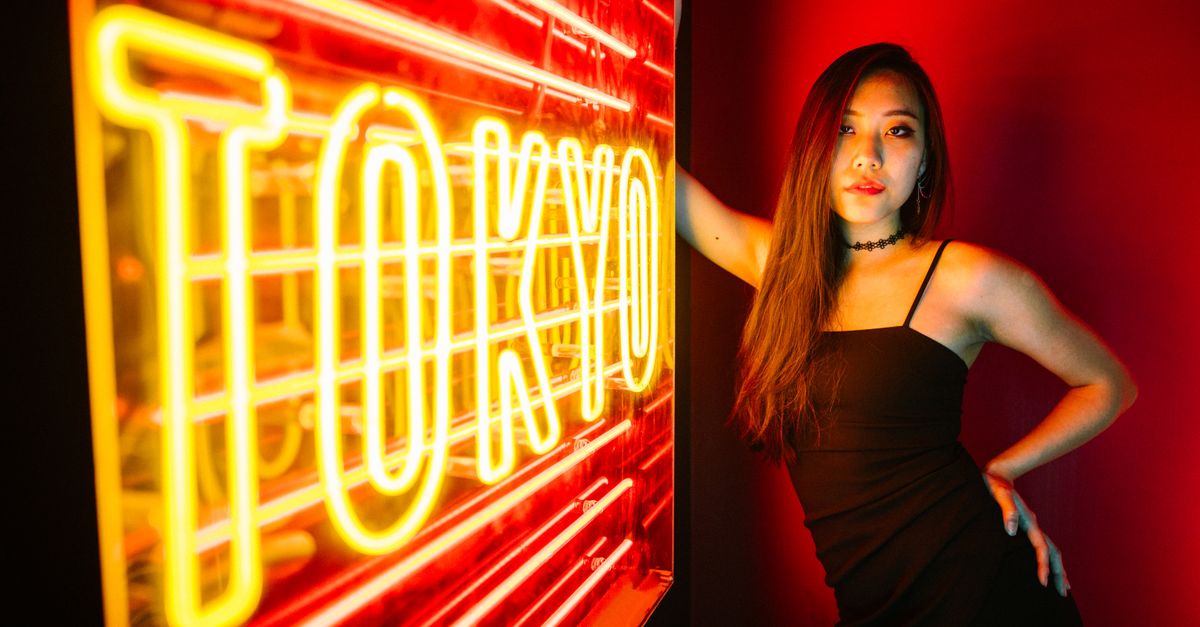 A stylish woman poses by a vibrant Tokyo neon sign, exuding modern urban nightlife.